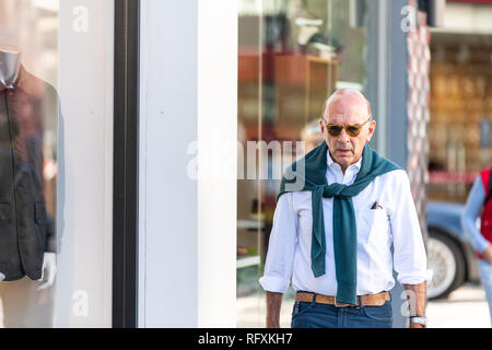 London, Regno Unito - 13 Settembre 2018: elegante uomo senior con la moda preppy maglione avvolto intorno a camminare sul marciapiede da parte dei negozi i negozi nella zona di Chelsea Foto Stock