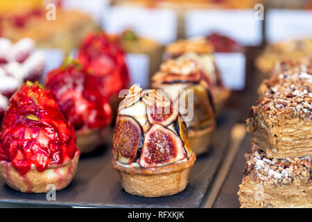 Visualizzazione di molte torte tortine farcite con la crema dessert su vassoi in pasticceria gourmet cafe pasticceria closeup con frutta fichi e fragole Foto Stock