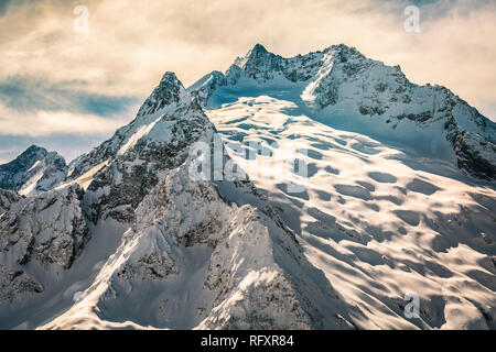 Bellissimo paesaggio colorato che mostra la bellezza delle montagne del Caucaso vicino alla città di Dombai, Russia al tramonto. Immagine dai toni Foto Stock