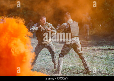 Festival storici Sambek altezze. Soldati di special purpose distacco lotta mano-a-mano combattimento in fumo arancione sul campo di battaglia Foto Stock