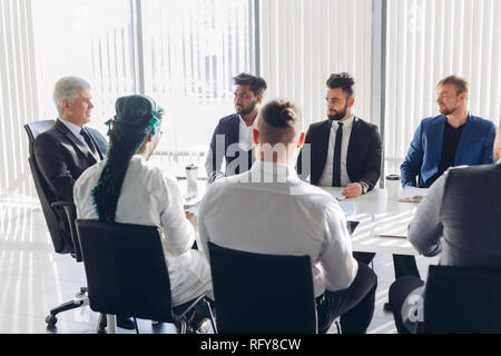 Maschio e multirazziale i dirigenti aziendali a discutere il progetto seduti ad un tavolo per conferenza Foto Stock