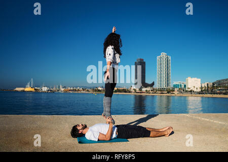 Bella giovane praticante acro yoga al mattino Foto Stock