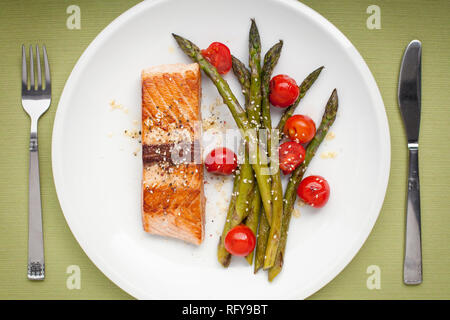 Filetto di salmone con asparagi e pomodori ciliegia sulla piastra bianca Foto Stock