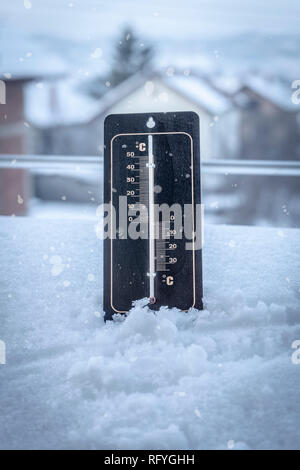 Un termometro impostato nella neve e misura la temperatura durante la nevicata Foto Stock
