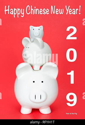 Felice Anno Nuovo Cinese, l'anno del maiale con tre piggy banche in varie dimensioni impilati gli uni sugli altri su sfondo rosso. Felice Anno Nuovo Cinese Foto Stock