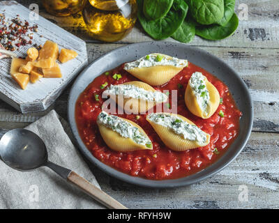 Cucinate la pasta conchiglioni ripieni di spinaci e formaggio, la salsa di pomodoro sulla piastra Foto Stock