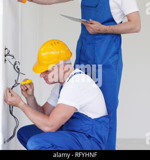 Due costruttori che lavorano con l'elettricità in ambienti chiusi in casa nuova Foto Stock