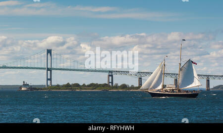 Una vista di un due-master yacht a vela in parte anteriore del Newport Bridge e Rose Island Lighthouse, Rhode Island Foto Stock
