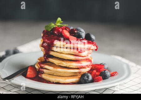 Frittelle con frutti di bosco e salsa su piastra. Tonica immagine. Gustosi pancake Foto Stock