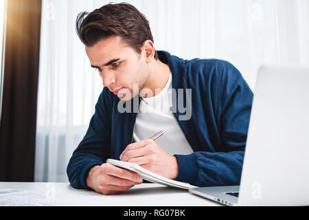 Concentrato di manager che lavora sul computer portatile e la lettura di informazioni in un moderno ufficio spale. Imprenditore si siede alla sua scrivania e progetto prepearing Foto Stock