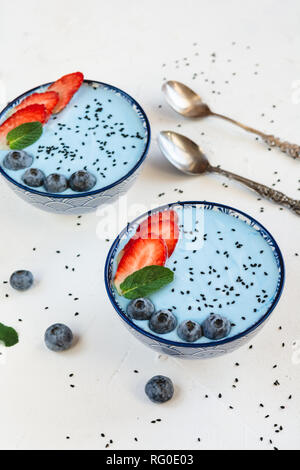 Blu frullato di yogurt fatto con blue spirulina polvere, fragole e mirtilli. Foto Stock