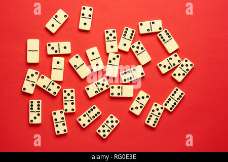 Piatto concetto laici. Giochi da tavolo pubblicazioni. domino pezzi sullo sfondo rosso con copia spazio . Foto Stock