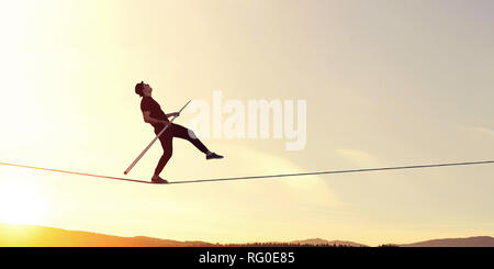 Ropewalker in black hat corda a piedi in alto nel cielo . I supporti misti Foto Stock