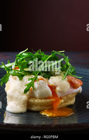 Sandwich con uovo in camicia, salmone affumicato e formaggio decorato con foglie di rucola Foto Stock