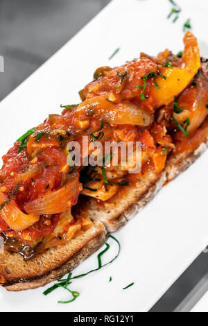 Il portoghese caldeirada de Peixe piccante cipolla pomodoro e peperoni stufato di pesce su rustiche tiborna toast stile tapas Foto Stock