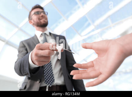 Immagine ritagliata di agente immobiliare di dare le chiavi di casa a uomo in ufficio Foto Stock