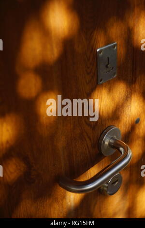 Brown porta in legno con maniglia cromata e round raggi solari Foto Stock