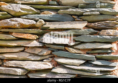 Pietra ardesia impilati su un rustico di muro di pietra Foto Stock