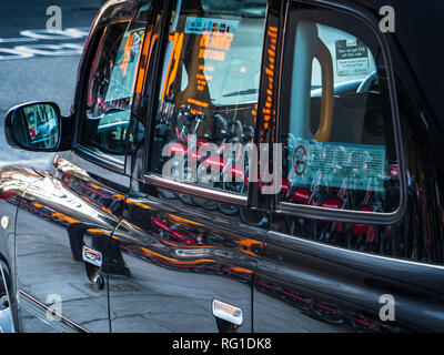 Taxi di Londra, London Black Cab - luci di strada e biciclette a noleggio riflessa dal lato di un taxi a Londra nel centro di Londra Foto Stock