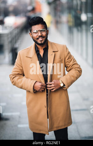 Felice barbuto moderno indiano giovane imprenditore sorridente nelle strade all'aperto Foto Stock