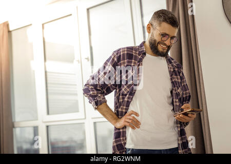 Tall barbuto dai capelli scuri uomo in una camicia a scacchi una buona sensazione Foto Stock