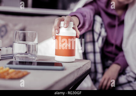 Incentrato sulla fotografia di mano femminile che assumendo compresse Foto Stock