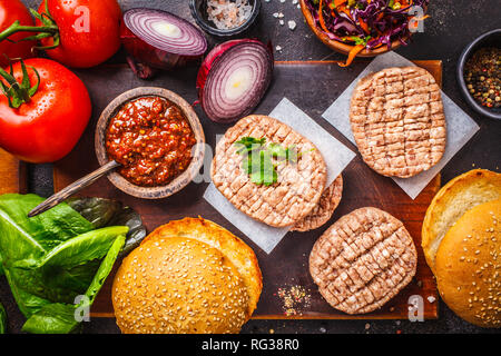 Ingredienti per gli hamburger di carne con verdure e coleslaw su uno sfondo scuro, vista dall'alto, copia dello spazio. Foto Stock