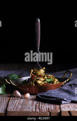Spaghetti con spinaci e pomodori secchi. Forcella pestate in spaghetti su una piastra. Foto Stock