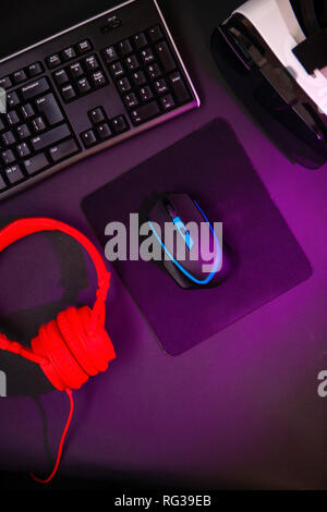 Vista dall'alto di un ingranaggio di gioco, mouse, tastiera, joystick, la cuffia auricolare VR nero su sfondo tabella. Gamer concetto di area di lavoro. Foto Stock