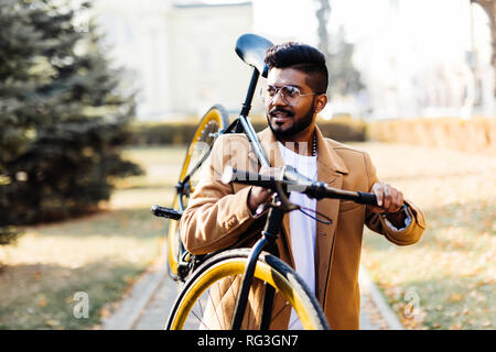 Giovani asiatici allegro imprenditore tenendo la bici in spalla in outdoor city. Felice successo business man in bicicletta andare al lavoro con la bici in città Foto Stock