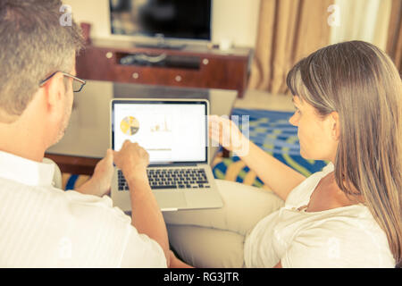 Un uomo e una donna sono al lavoro su una presentazione su un computer portatile in salotto Foto Stock