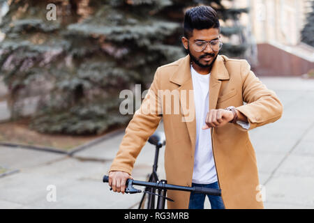 Bello tanga indiano godendo di una bicicletta e di controllo di tempo sul suo orologio. Foto Stock