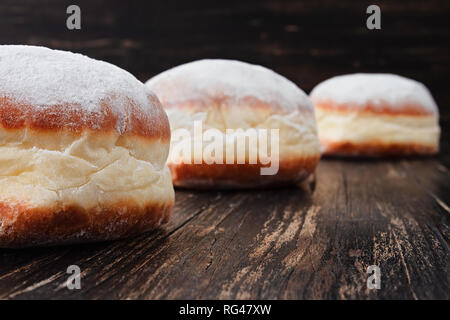 Appena fatti riempito le ciambelle con marmellata e ricoperta di zucchero a velo su una tavola in legno rustico Foto Stock