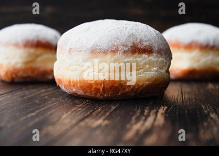 Appena fatti riempito le ciambelle con marmellata e ricoperta di zucchero a velo su una tavola in legno rustico Foto Stock