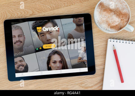 Il sito web Grindr funzioni su un iPad dispositivo tablet pc che si appoggia su una tavola di legno accanto a un blocco note (solo uso editoriale). Foto Stock