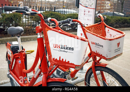 Una coppia di rosso e bianco UH Bikes Cleveland biciclette parcheggiate sul marciapiede in downtown Cleveland, Ohio, USA, parte del pubblico regime di moto. Foto Stock