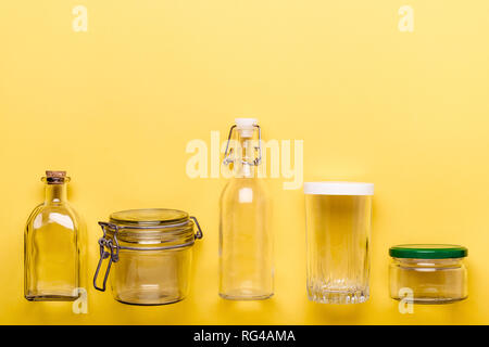 Set di vasetti e bottiglie di vetro su sfondo giallo. Zero il concetto di plastica. Foto Stock