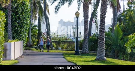 Due donne a piedi lungo la spiaggia di Palma Lago Trail in Palm Beach, Florida, con West Palm Beach in vista attraverso l'Intracoastal Waterway. (USA) Foto Stock