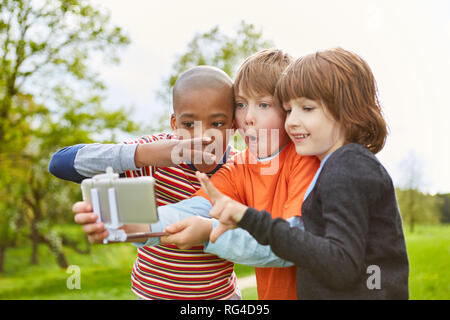 Tre bambini a fare ritratti per un selfie foto con lo smartphone sul Selfie Stick Foto Stock