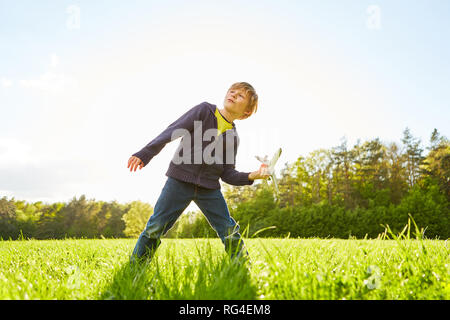 Ragazzo gioca nel parco con un modello di aeroplano come un simbolo per i sogni e viaggi Foto Stock