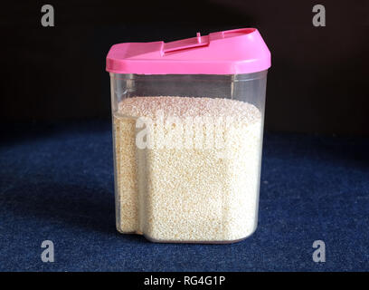 Il SESAMO in plastica trasparente contenitore da cucina con cappello rosa su sfondo nero su un tavolo coperto tovaglia jeans vista frontale di close-up Foto Stock
