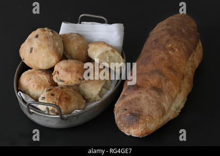 Appena cotto al forno di pasta acida pane fatto in casa e panini con semi - qualità rustico. Panini giacente in antica cestello di metallo con igienico. Splendido e pittoresco im Foto Stock