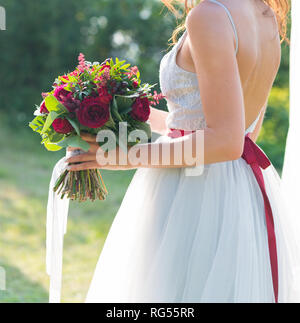 La sposa è in possesso di un colore rosso brillante matrimonio bouquet di fiori freschi e eucalipto Foto Stock