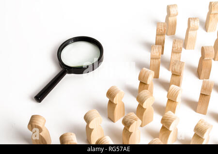 Figure in legno di persone guardano la lente di ingrandimento. Ricerca di risposte alle domande, le ricerche per la casa o per il lavoro. Risoluzione dei problemi e le attività di auto-org Foto Stock