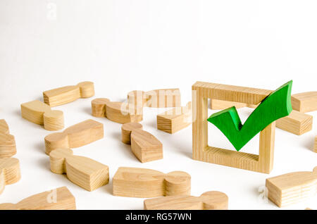 Segno di spunta verde si erge nel mezzo della giacente figure di persone. Votazioni e elezioni concetto. Referendum, rivoluzione. accordo di maggioranza. La pace, l'ordine, Foto Stock