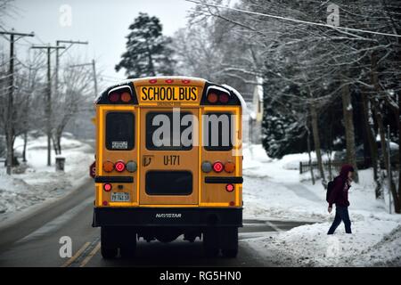 South Elgin, Illinois, Stati Uniti d'America. Una scuola bus si fermava a goccia di uno studente dopo la scuola durante un Midwestern neve nella zona di Chicago. L'inverno può essere duro i Foto Stock