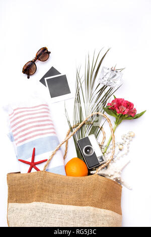 Accessori da spiaggia in un sacchetto di paglia su sfondo bianco Foto Stock