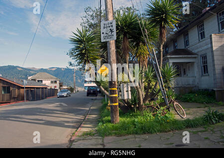 La bicicletta è arrugginito e dimenticata, accanto ad un simbolo di attenzione i driver di avvertimento di bambini che giocano per le strade di Bolinas, CA. Foto Stock