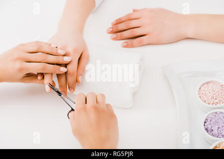 Vista ritagliata della manicurist il taglio di cuticole con le forbici Foto Stock