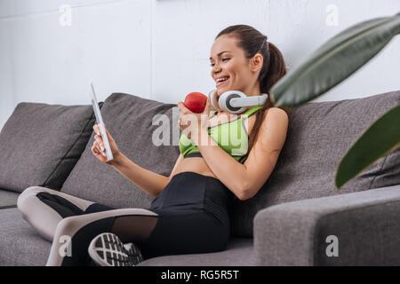 Sportive con cuffie Apple di contenimento e con tavoletta digitale in casa Foto Stock